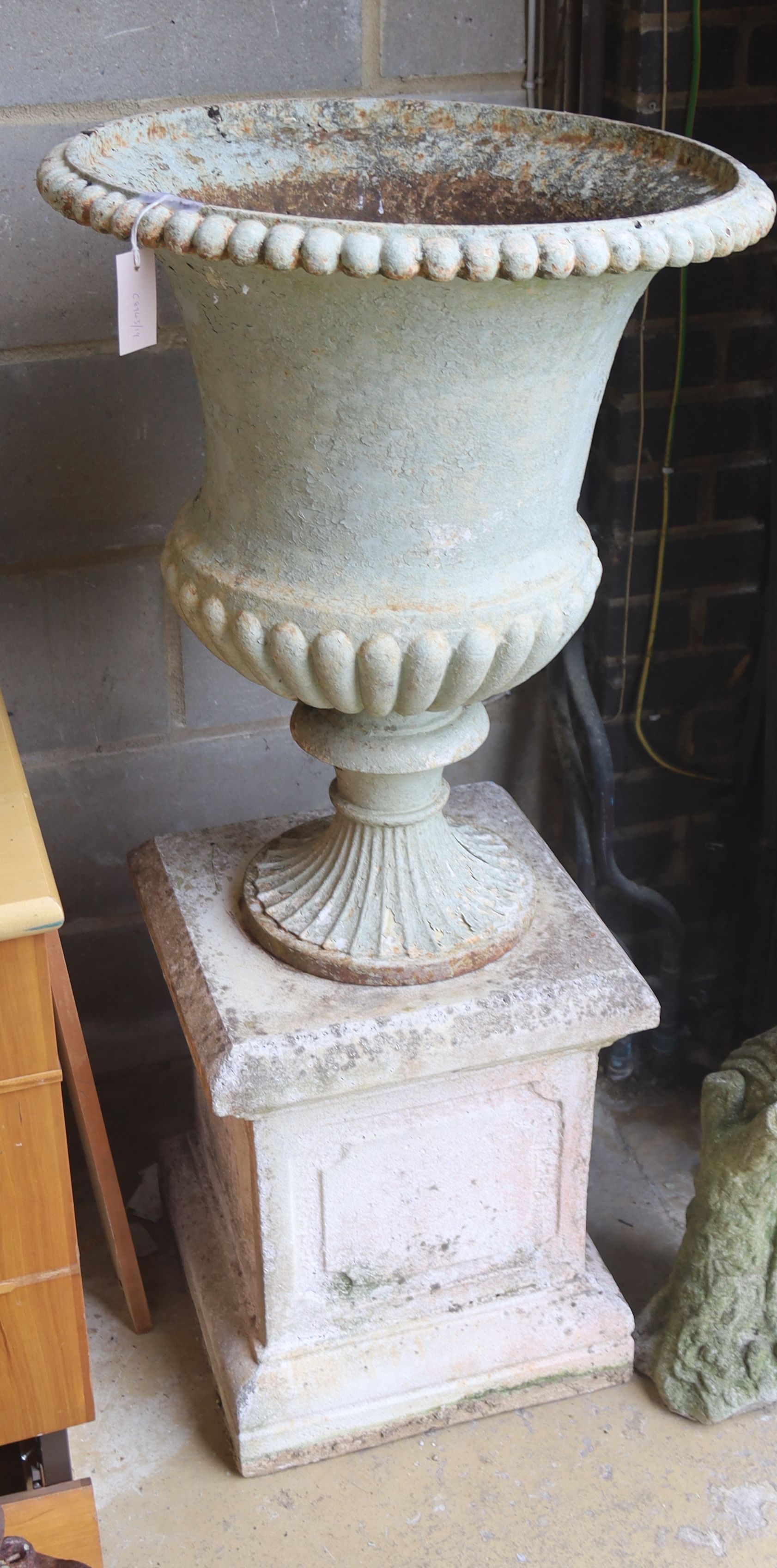 A Victorian white painted cast iron campana garden urn, diameter 56cm, height 118cm on a later reconstituted stone pedestal